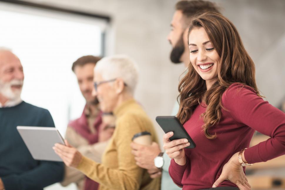 Free Image of Happy female office worker checking messages on her smartphone 