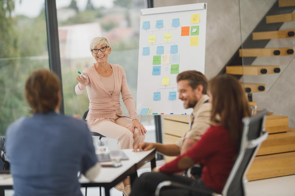 Free Image of Senior woman manager showing presentation on the whiteboard to to colleagues 