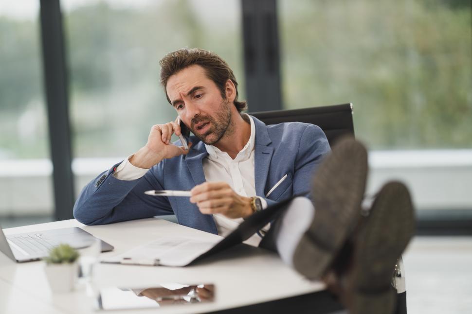 Free Image of Male executive sitting in office with feet up at the desk 