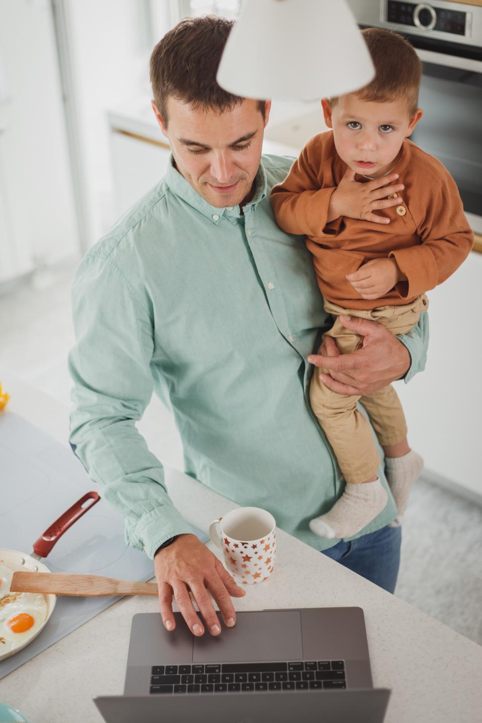 Free Image of Young dad using laptop with his son during breakfast at home 