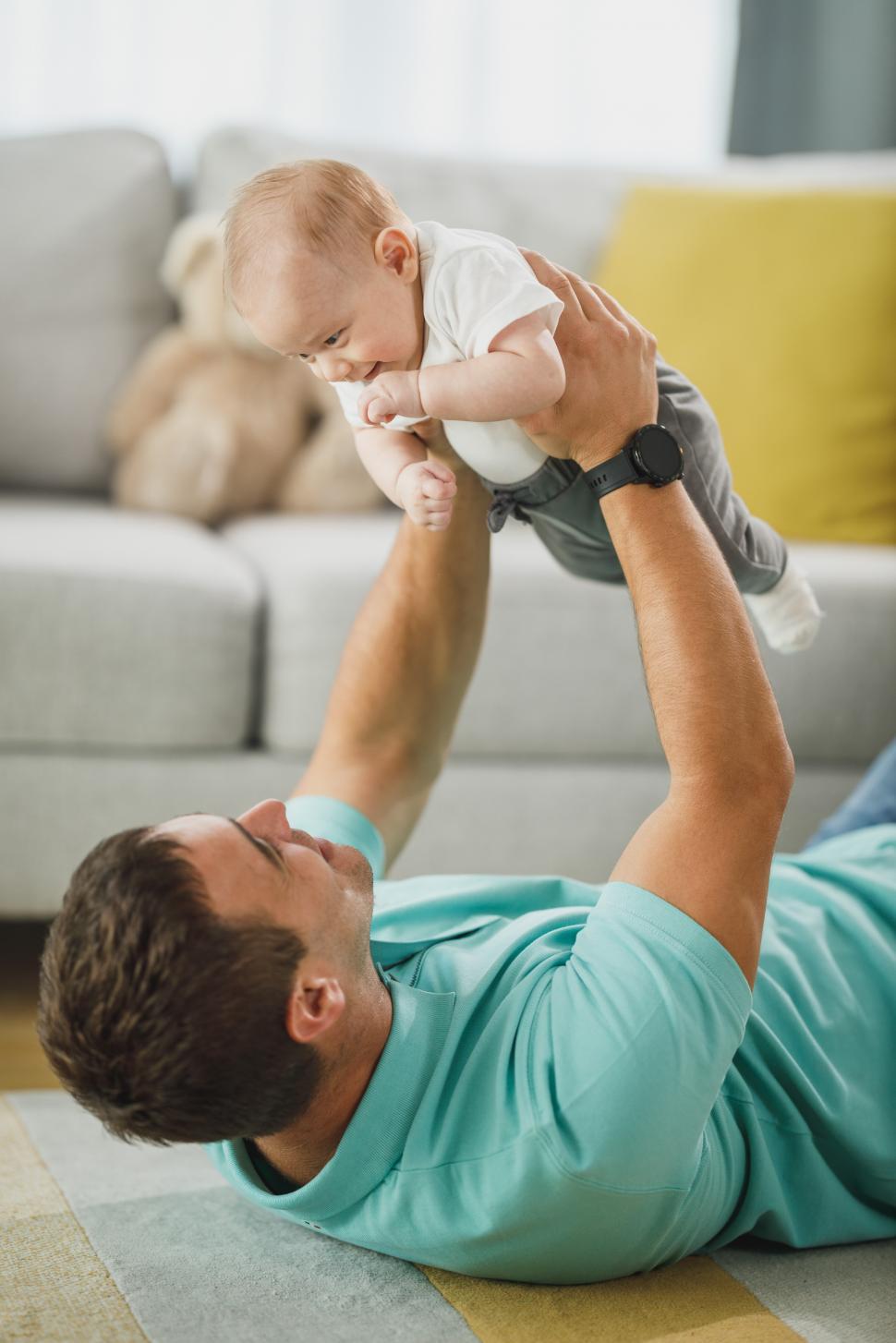 Free Image of Happy dad holding and playing with his little son in home 