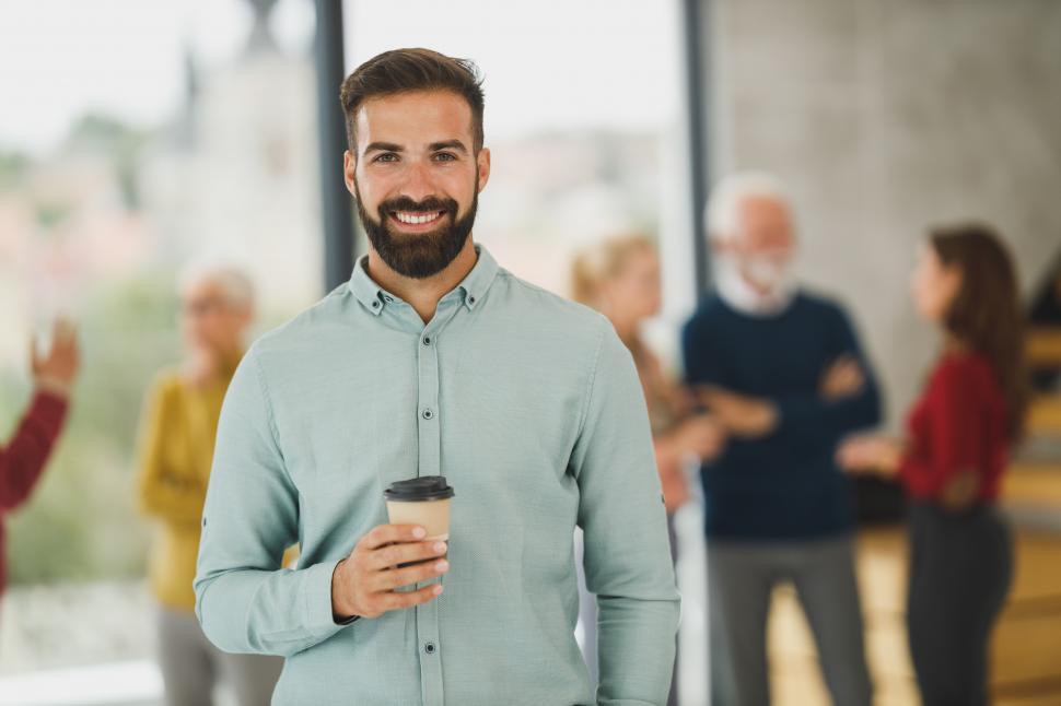 Free Image of Male executive with paper coffee cup in office - looking at came 