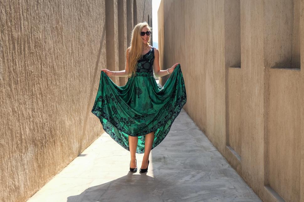 Free Image of Woman in green dress posing and standing in narrow lane - lookin 