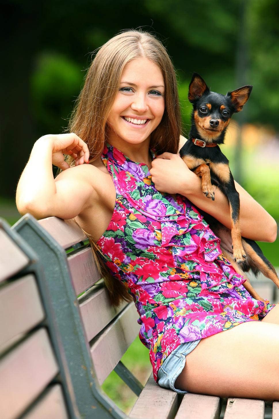 Free Image of Young happy girl with her cute dog on a park bench outdoors 
