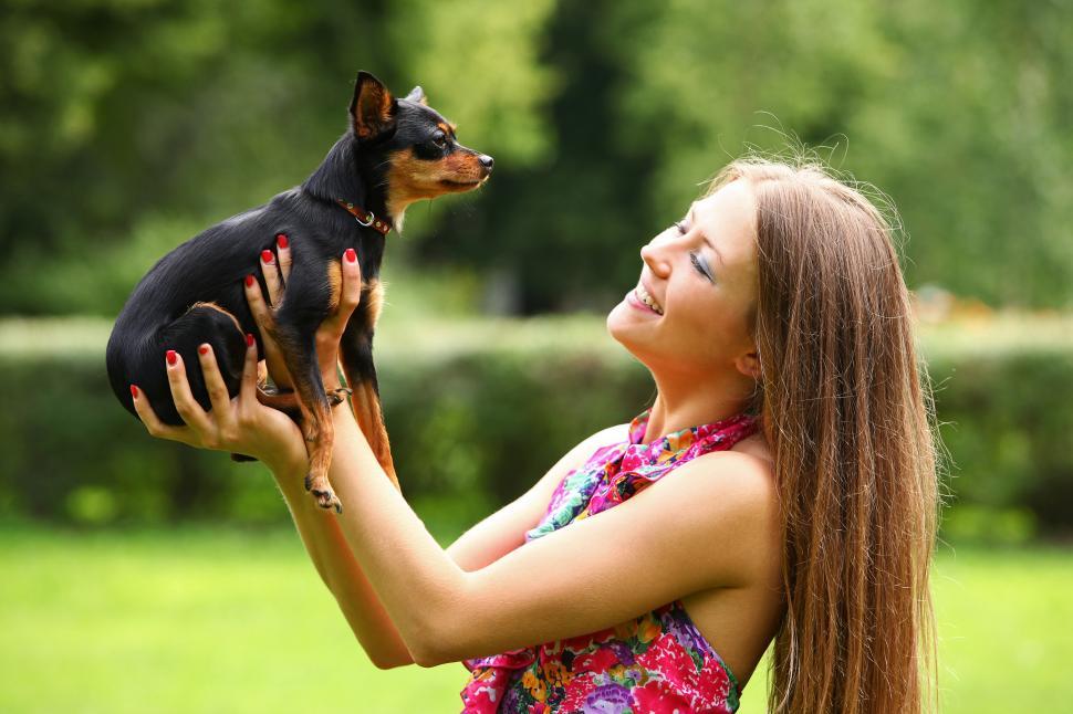 Free Image of Happy young woman holding up her small dog 