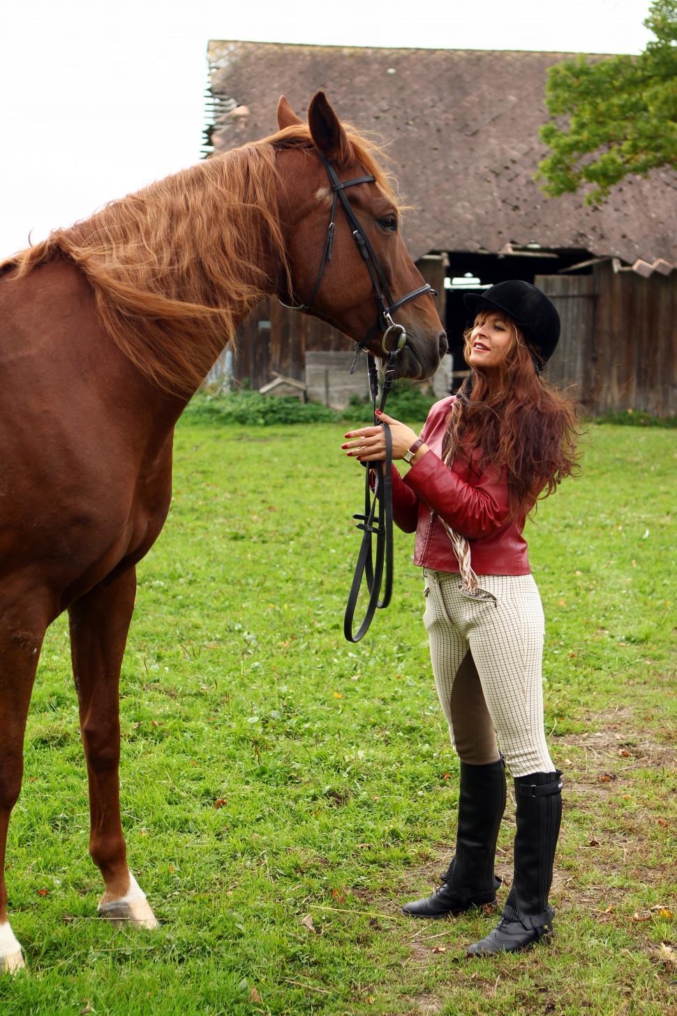 Free Image of Young woman in a field with her brown horse 