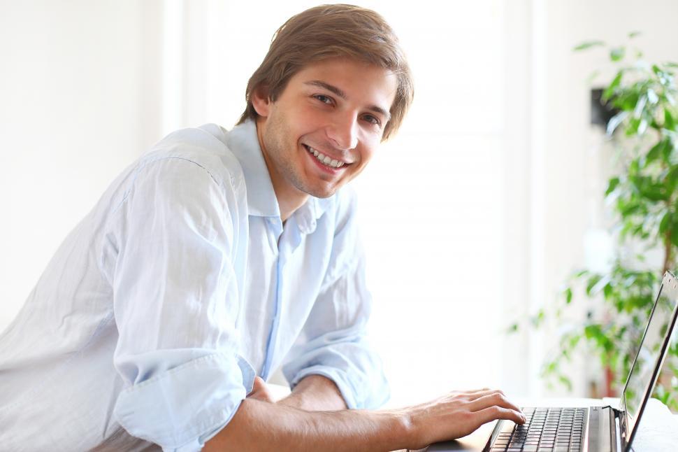 Free Image of Cheerful looking man at a laptop, looking at the camera 