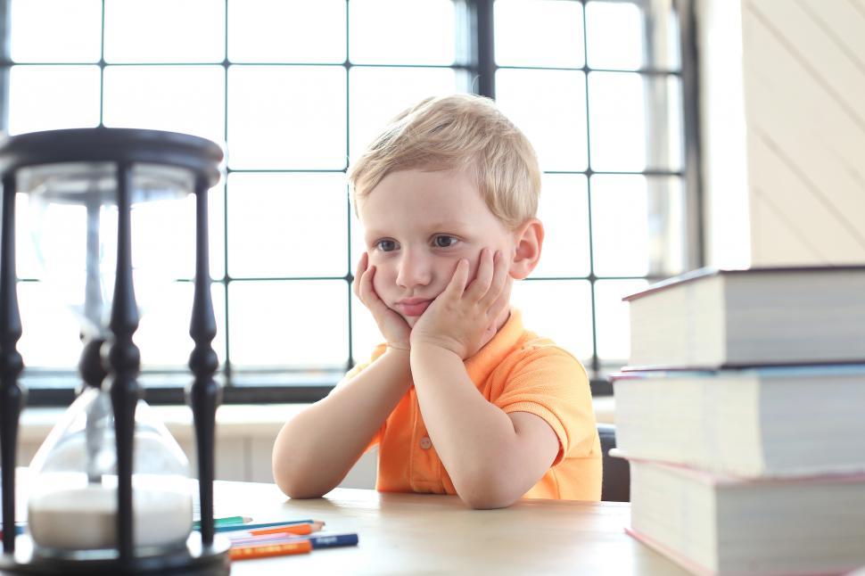 Free Image of Cute kid staring at an hourglass watching time pass 