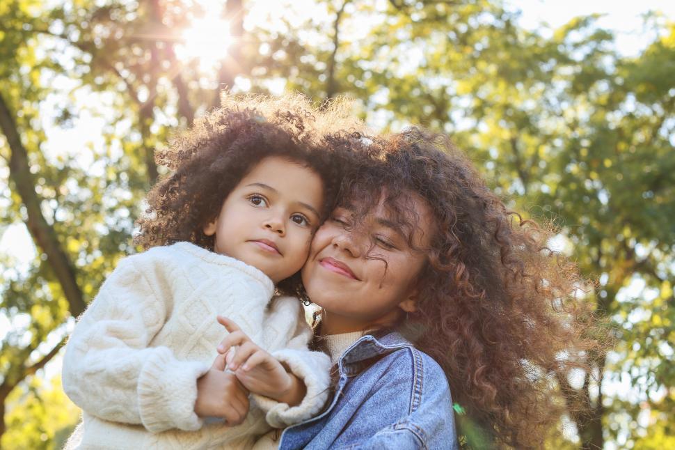 Free Image of Young smiling woman with eyes closed holding little girl in the 