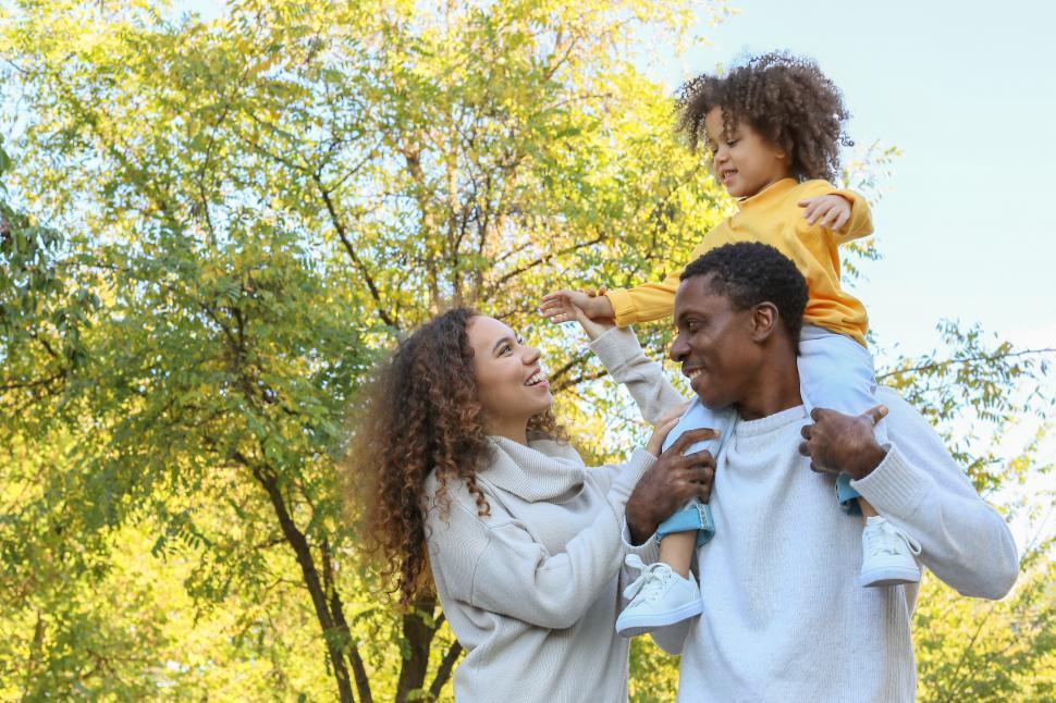 Free Image of Young smiling parents with daughter walking in the park - happy 