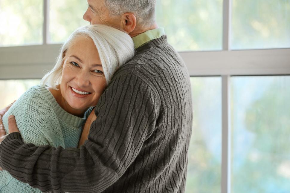Free Image of Happy Couple hugging each other near glass window at home - look 