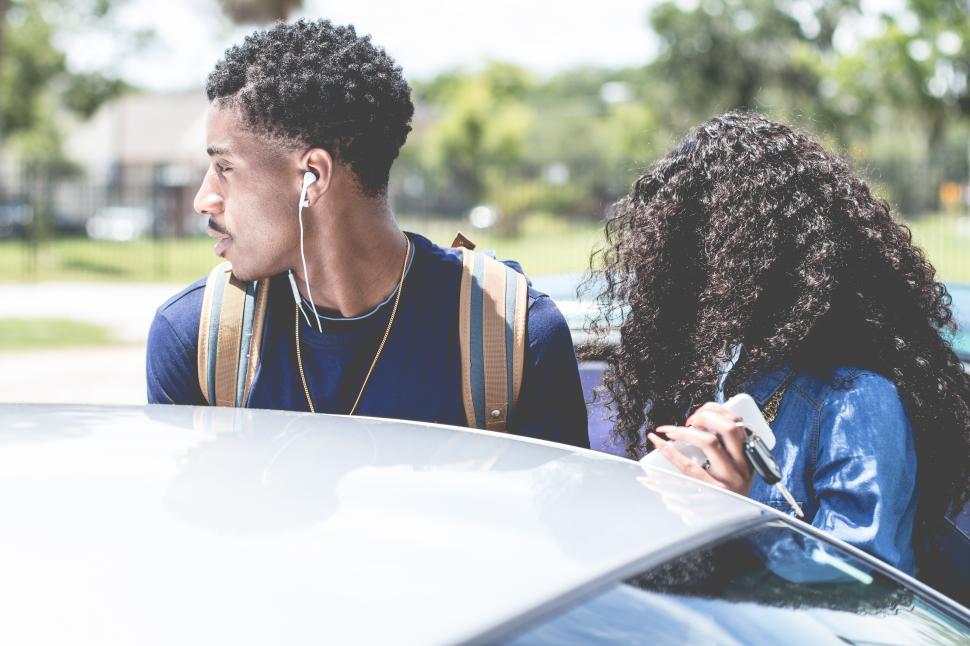 Free Image of Stylish couple standing beside a car 