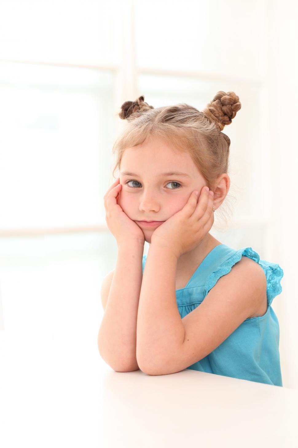 Free Image of Cute little girl at home, rester her face in her hands 