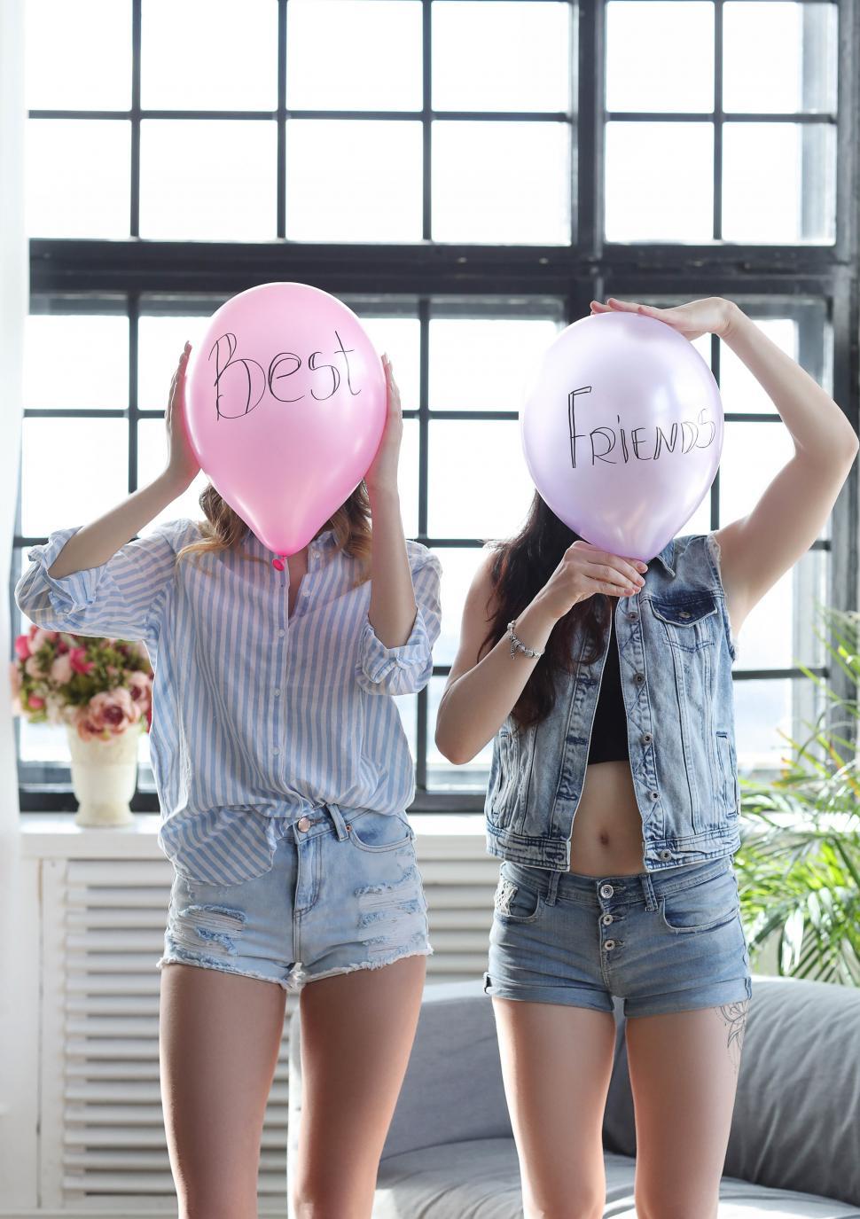Free Image of Best friends with balloons over their faces 