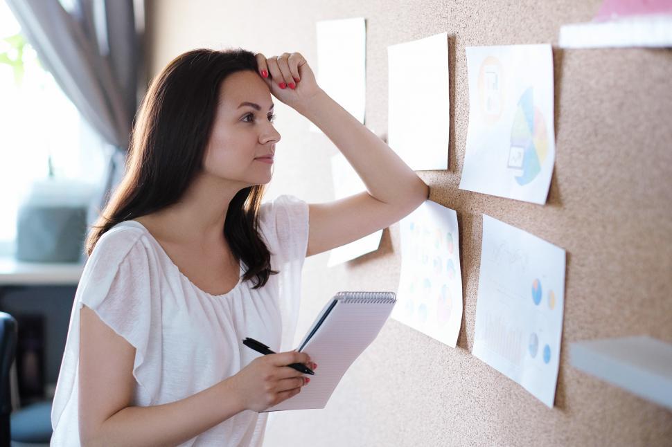 Free Image of Woman looking a charts on corkboard 