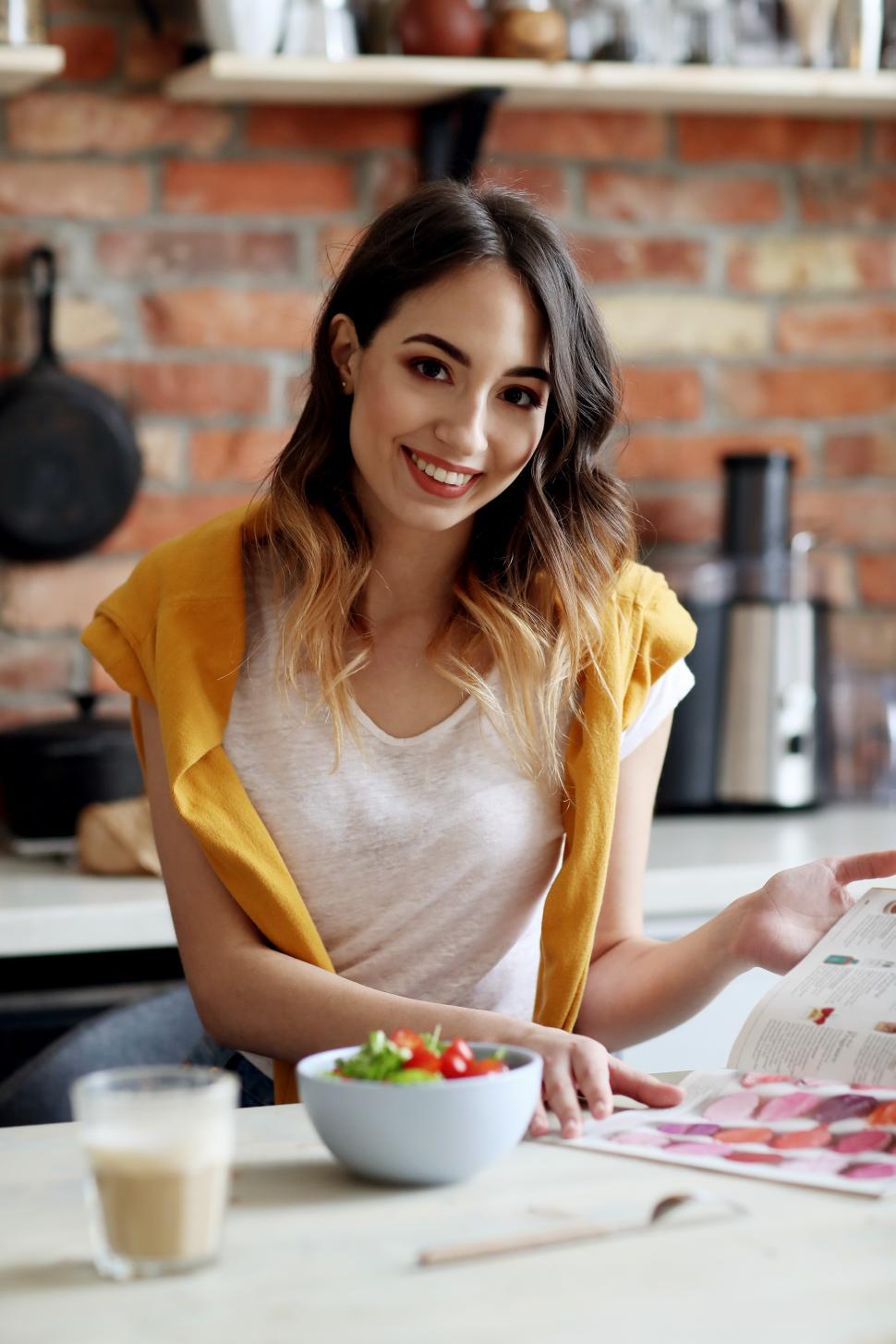 Free Image of Woman reading and eating at a counter 