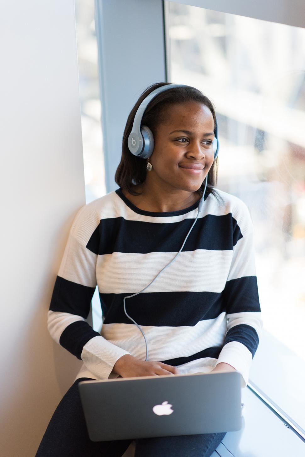 Free Image of Happy female using laptop with headphones in room 