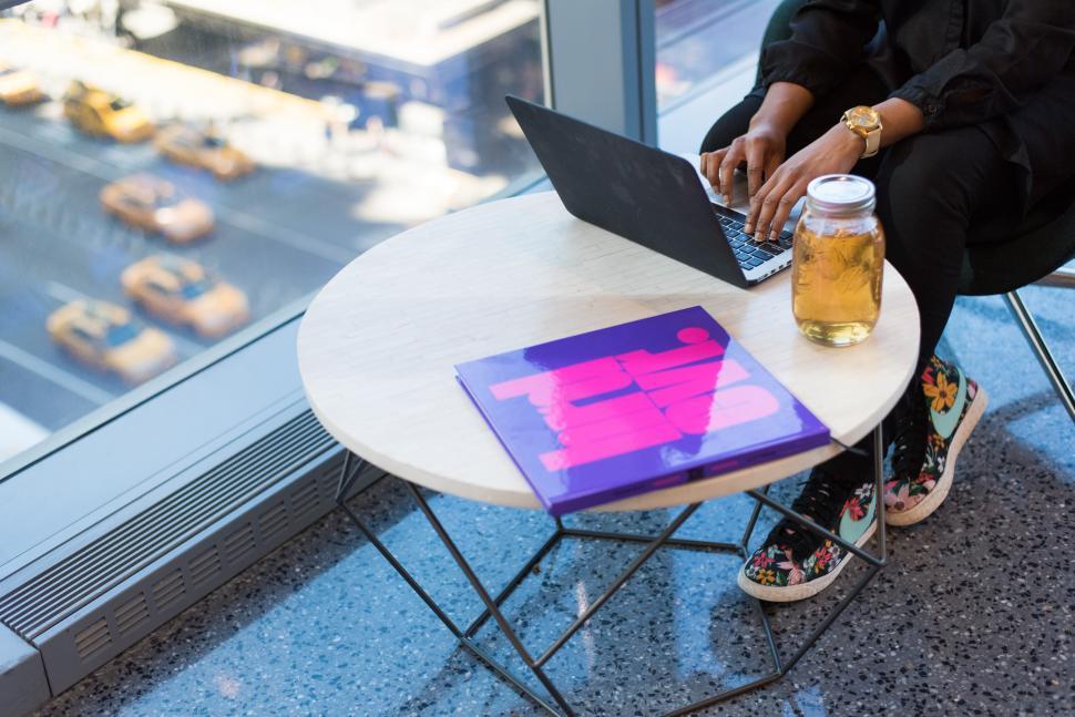 Free Image of Woman and laptop with mason jar and coffee table book 