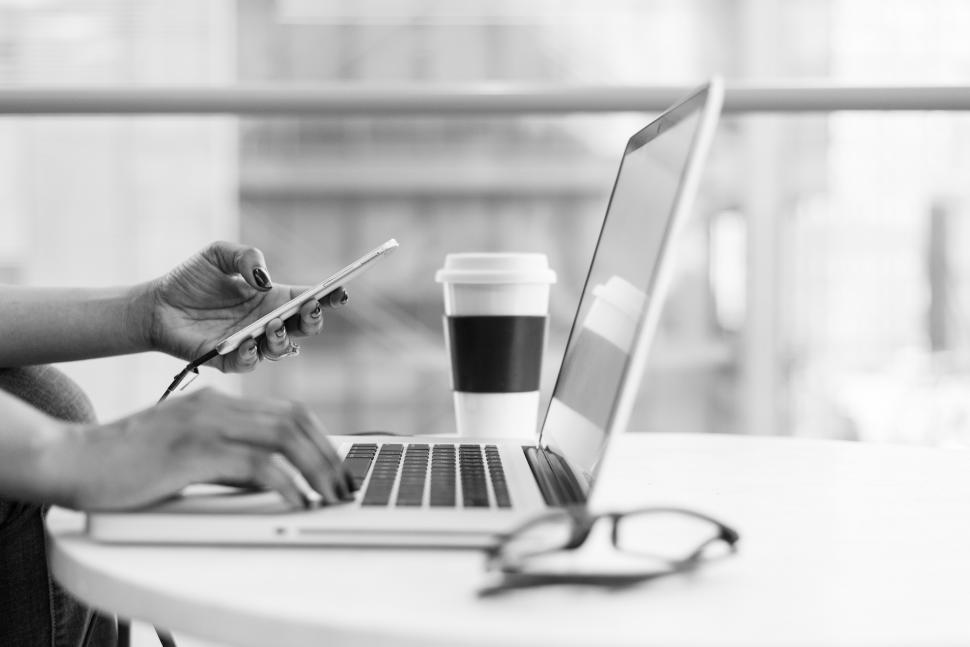 Free Image of Female programmer hands with cellphone and laptop - b&w 