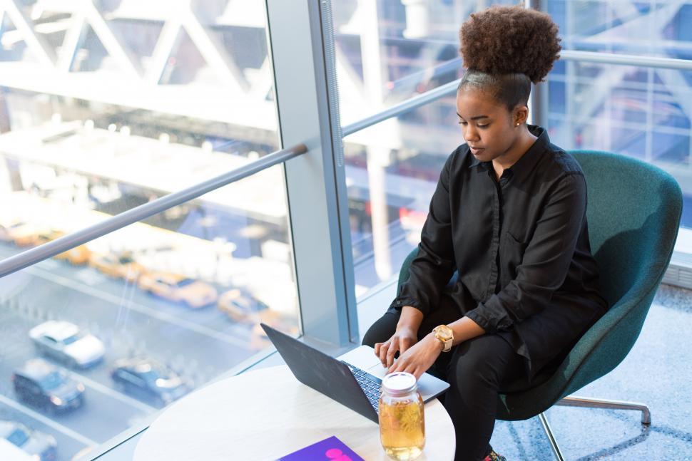 Free Image of Woman working on laptop with juice jar on table in office 