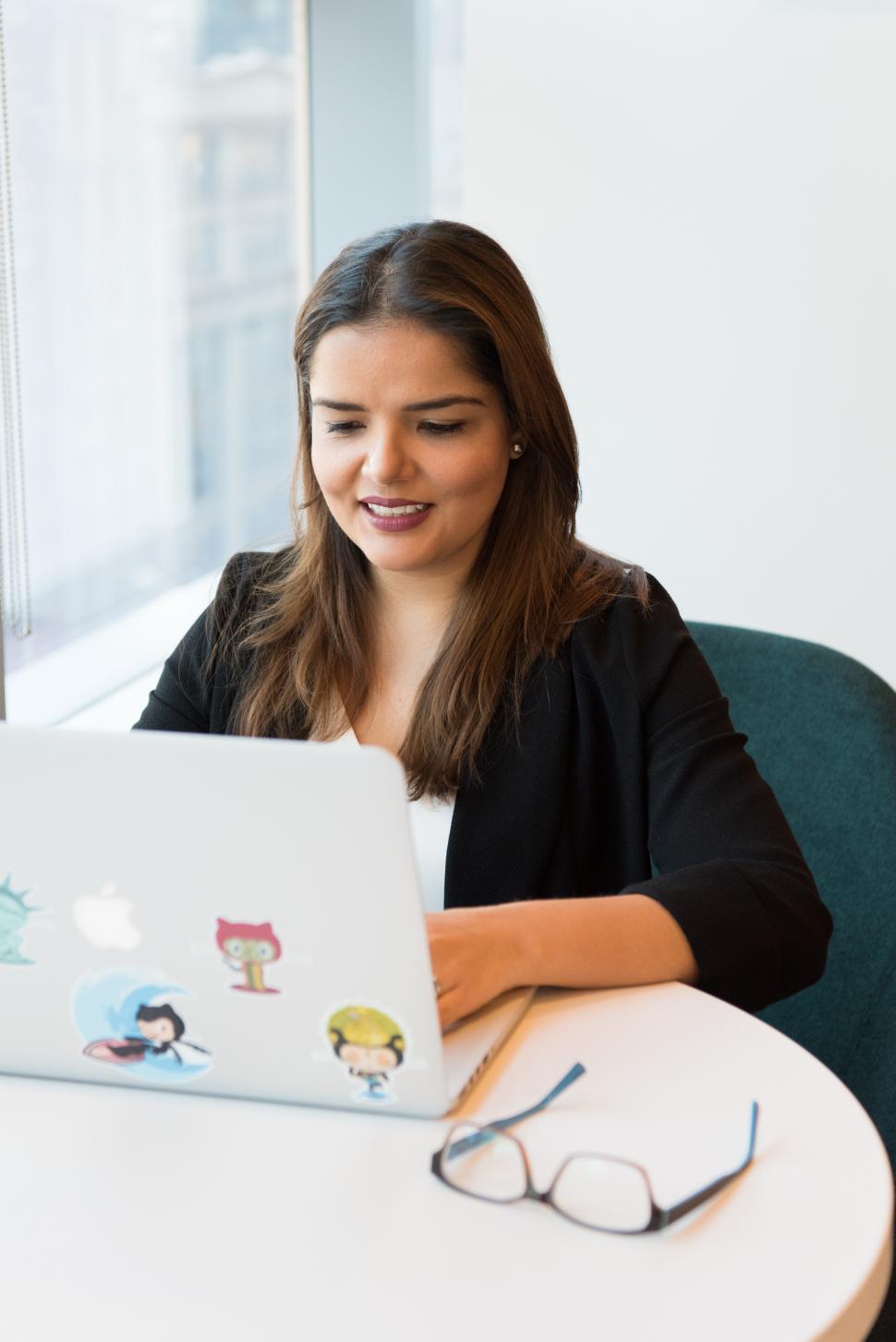 Free Image of Businesswoman smiling while looking at laptop screen in office 