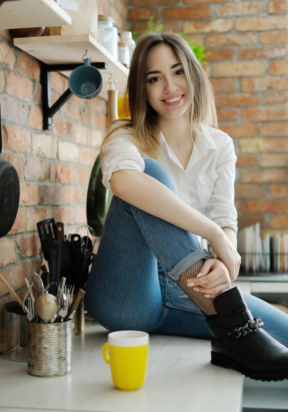 Free Image of Woman sitting on her kitchen counter 