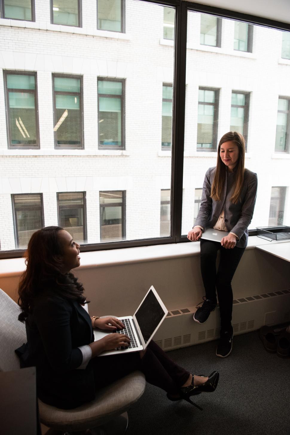Free Image of Happy Businesswomen with laptop near glass window 
