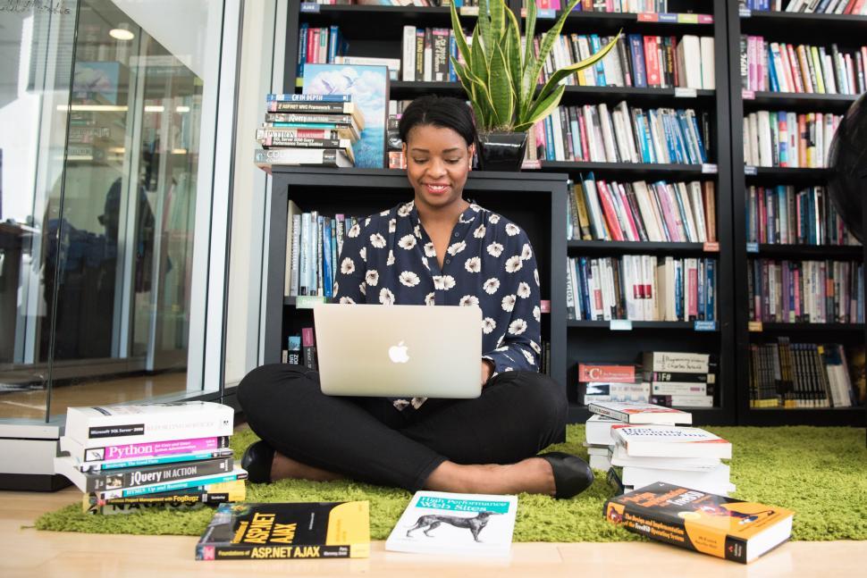 Free Image of Happy female developer with laptop in library 