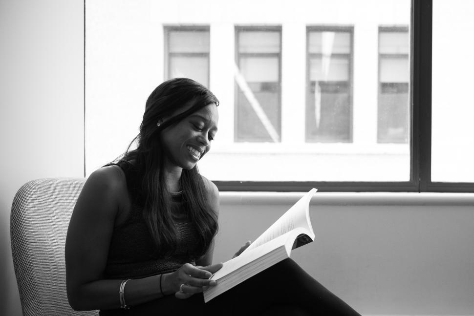 Free Image of Smiling woman with book - looking down at book 