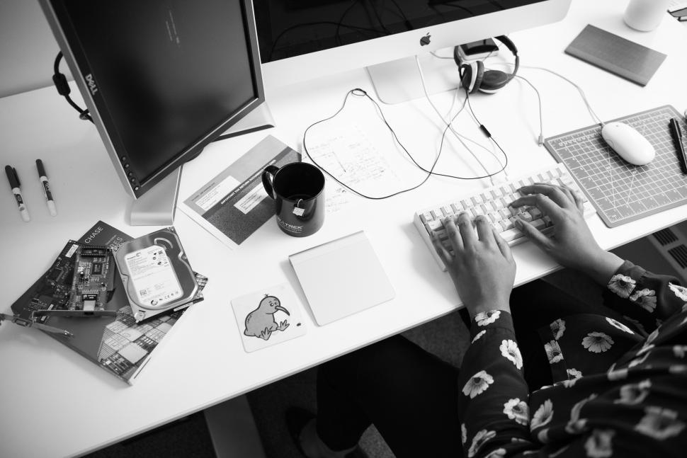 Free Image of Woman working on computer with coffee mug on desk 