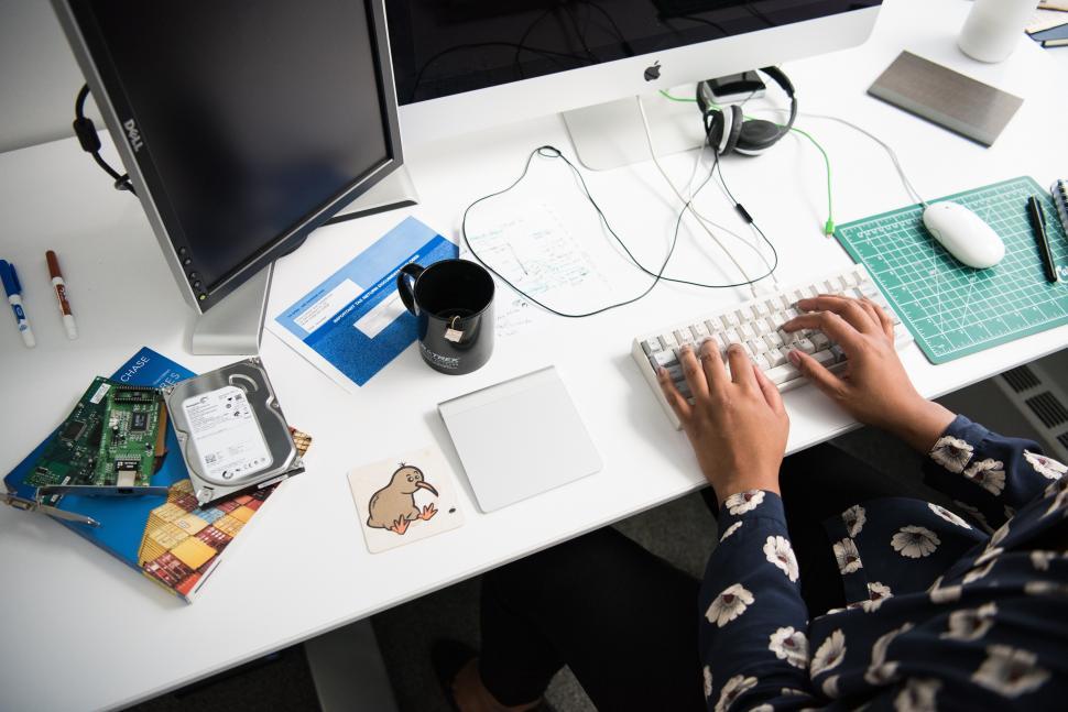 Free Image of Woman working on computer with coffee mug on desk 