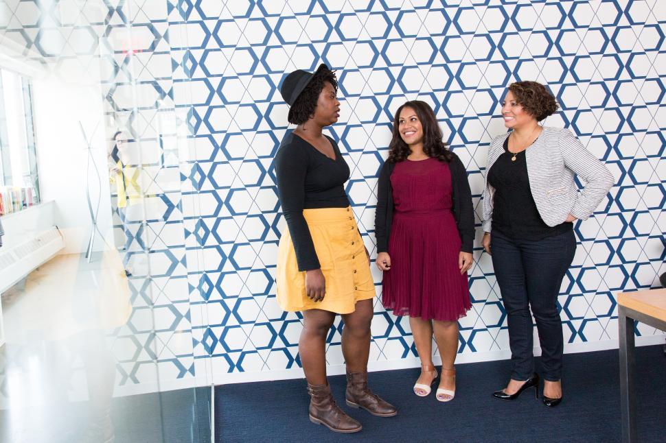 Free Image of Three Female co-workers talking and smiling in meeting room 