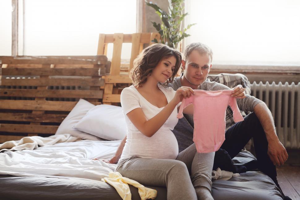Free Image of Pregnant couple with baby clothes 