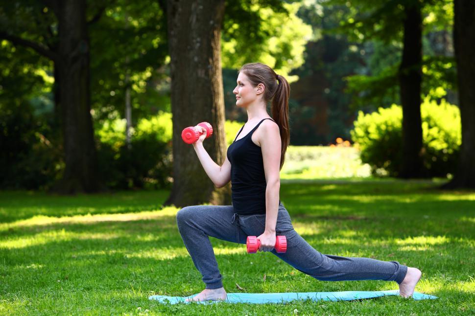 Free Image of Young woman doing lunges with dumbbells 