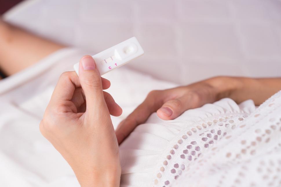 Free Image of Pregnant asian woman looking at ultrasound scan of baby and touching belly 