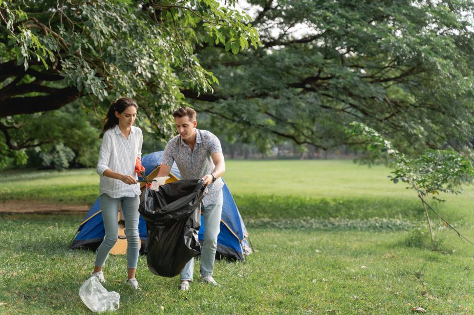 Free Image of Volunteer couple wearing gloves walking to to pick up garbage 