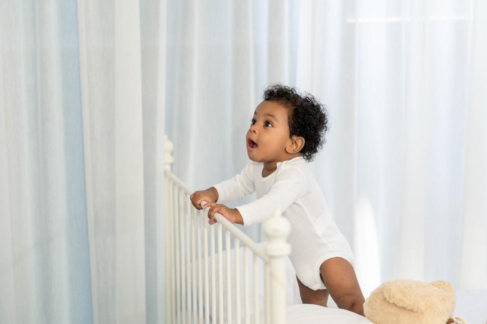 Free Image of Little baby boy climbs the head of the bed 