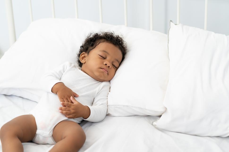 Free Image of Baby sleeping on a white mattress 