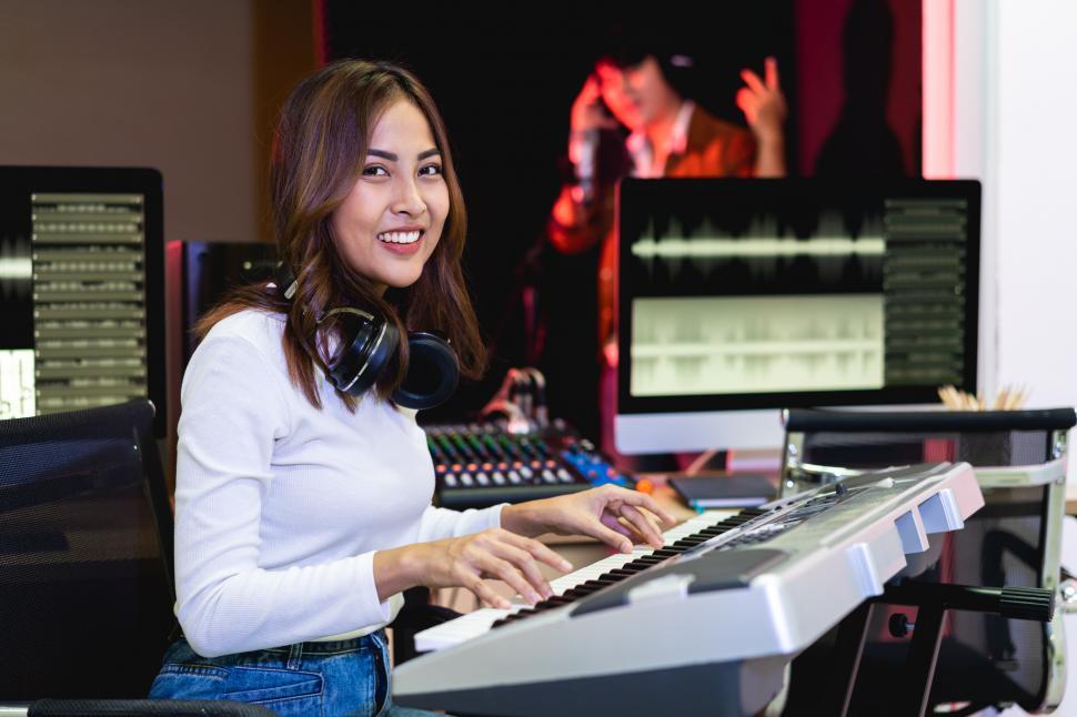 Free Image of Asian producer woman in white shirt standing by sound mixing console 