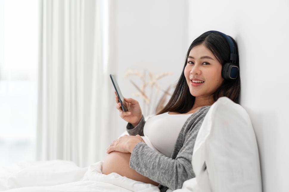 Free Image of Happy pregnant woman on bed and and touching her tummy 