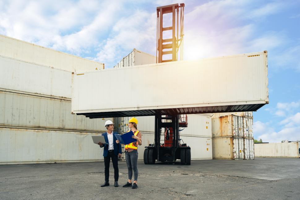 Free Image of two engineers hold a laptop, document for checking a shipment 