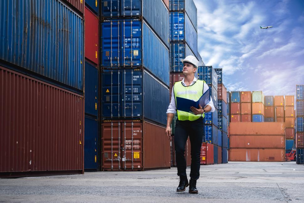 Free Image of Foreman holding document, walking and checking cargo 