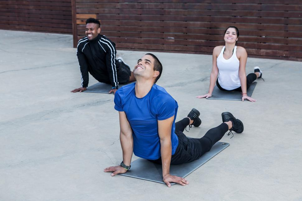 Free Image of Cheerful trainer showing Upward Facing Dog exercise for athletes 