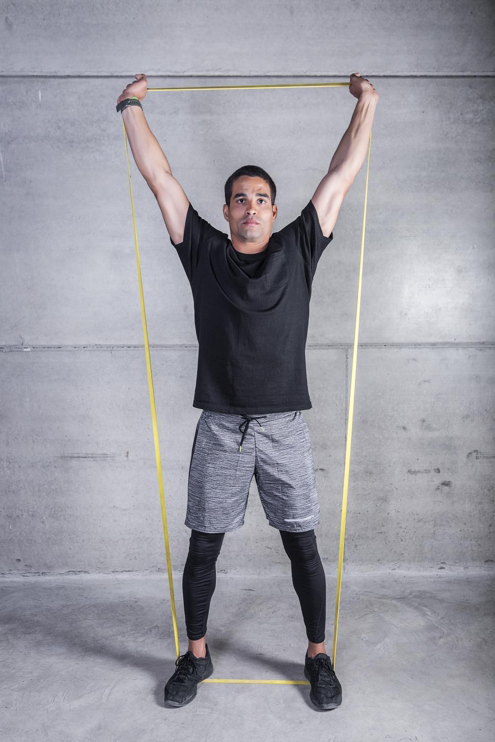 Free Image of Man with elastic band holding arms raised 
