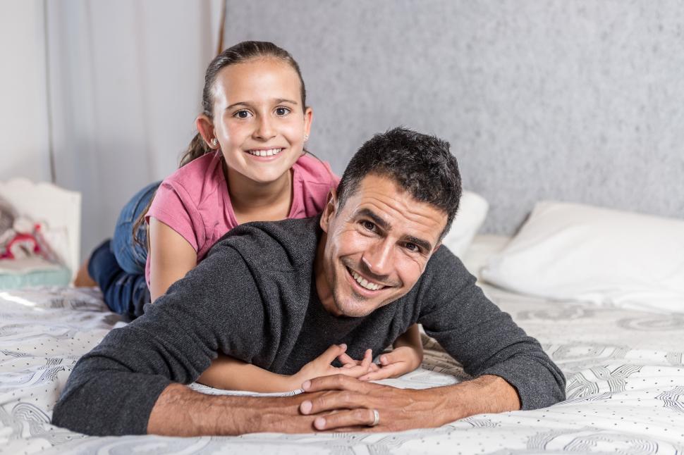 Free Image of Father and daughter cuddling on bed 