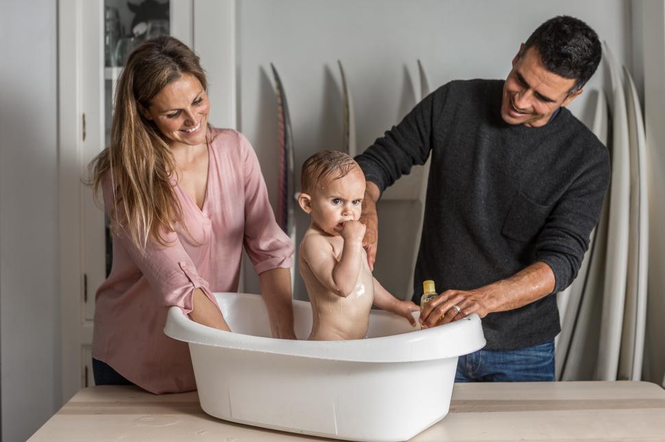 Free Image of Dad and mom bathe the baby in the bathtub 