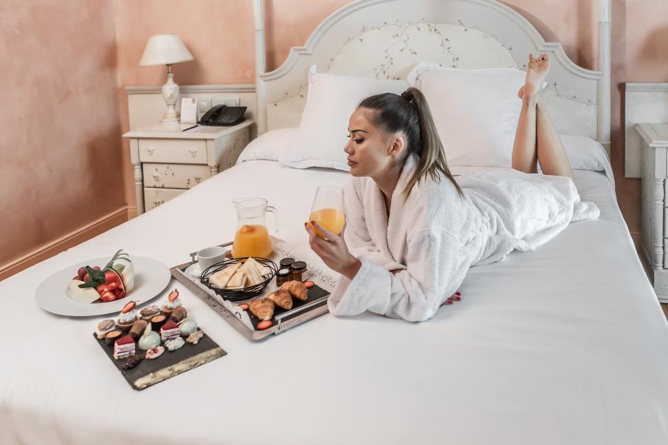 Free Image of Barefoot woman enjoying breakfast on bed 