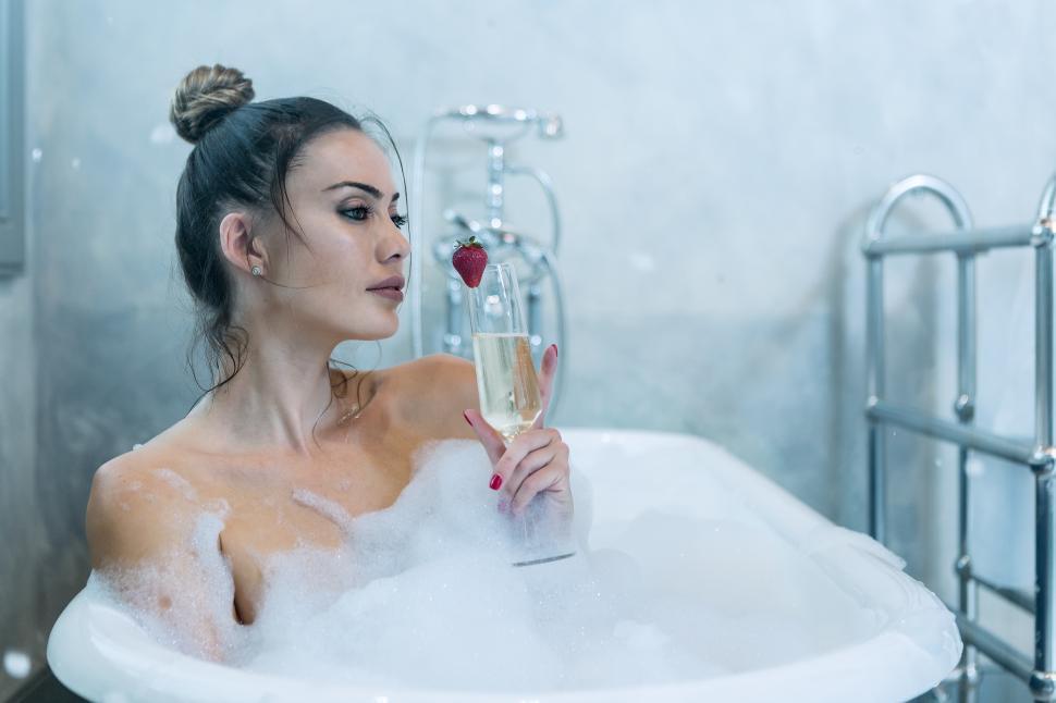 Free Image of Dreamy female with champagne taking bath 
