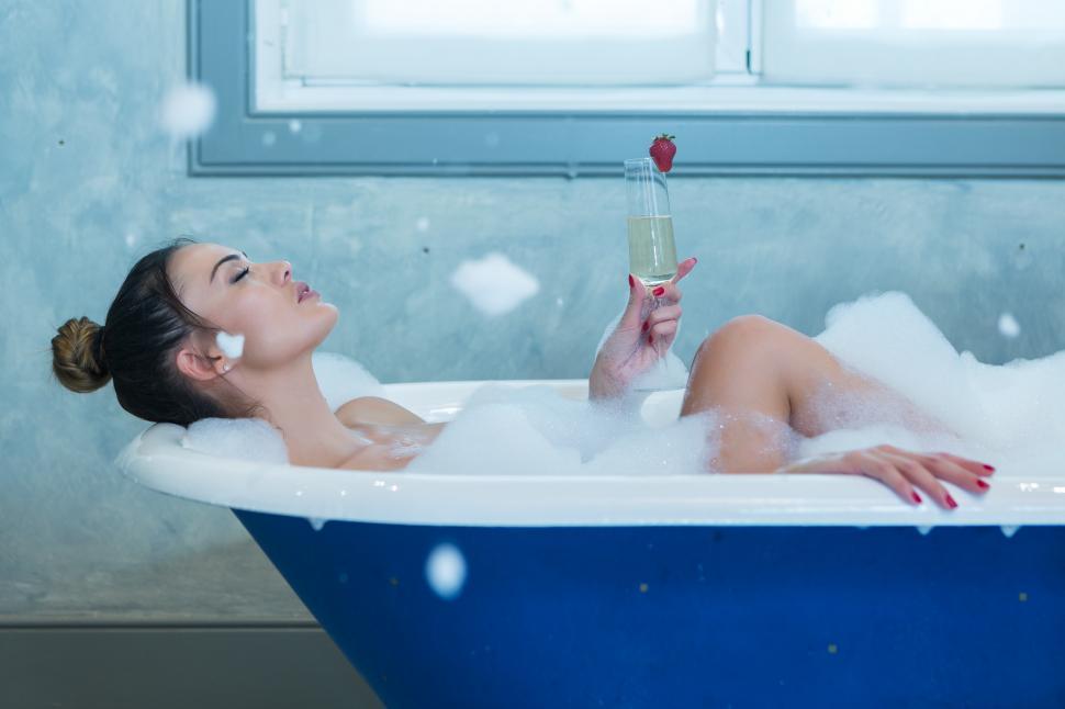 Free Image of Woman with champagne relaxing in foamy bathtub 