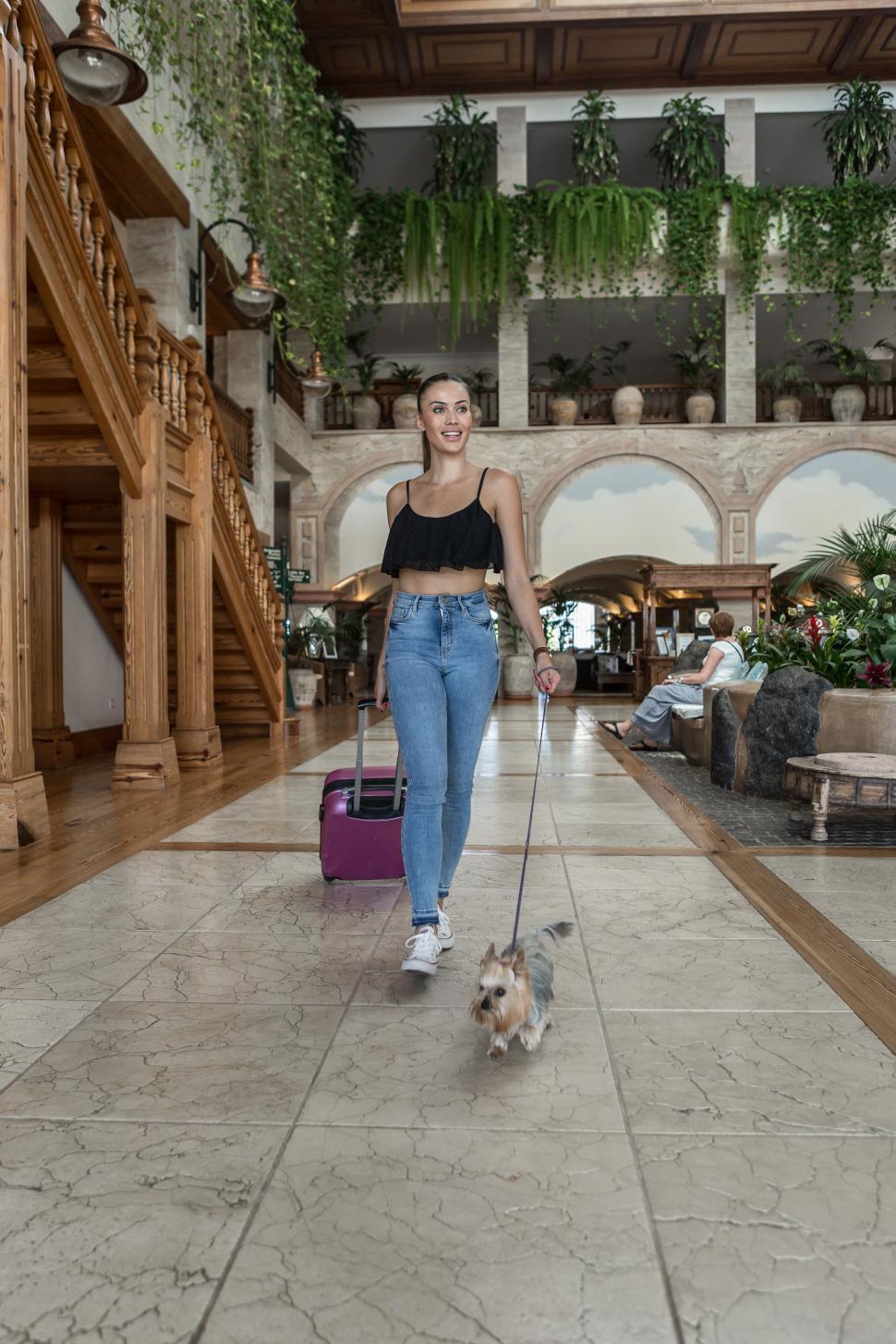 Free Image of Female traveler with dog walking in hotel 